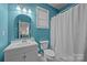 Small teal bathroom with a white vanity, an arched mirror, and a toilet at 1108 Longwood Ct, Matthews, NC 28104