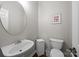 Clean half-bathroom with a white pedestal sink, a round mirror, and a toilet at 1108 Longwood Ct, Matthews, NC 28104