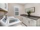 Bright laundry room featuring granite countertops, white cabinets, a window with blinds, and modern appliances at 113 Callandor Ct, Troutman, NC 28166