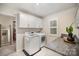 Well-lit laundry room with gray granite countertops, modern washer and dryer, and white cabinets for ample storage at 113 Callandor Ct, Troutman, NC 28166