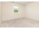 Light filled bedroom features a window with backyard views, and neutral colored walls and carpet at 1313 Forkhorn Dr, Monroe, NC 28110