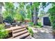 Landscaped backyard with stone patio, deck, mature trees, and a storage shed at 2124 Chambwood Dr, Charlotte, NC 28205