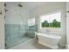 Luxurious bathroom with a glass-enclosed shower, freestanding tub, and nature views from the window at 3622 E Brief Rd, Monroe, NC 28110
