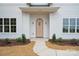 A close-up of the charming wooden front door, framed by elegant sconces and manicured landscaping at 3622 E Brief Rd, Monroe, NC 28110