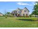Charming two-story brick home with manicured lawn, mature trees, and colorful landscaping for inviting curb appeal at 409 Wheatberry Hill Dr, Matthews, NC 28104