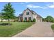 Stately brick home with well-manicured lawn, mature trees, and a long driveway leading to a spacious three-car garage at 409 Wheatberry Hill Dr, Matthews, NC 28104
