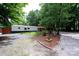 A single-story home featuring a manicured lawn, mature trees, and a gravel driveway at 475 Dot Faris Rd, Catawba, SC 29704