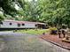 A single-story home featuring a manicured lawn, mature trees, and a gravel driveway at 475 Dot Faris Rd, Catawba, SC 29704