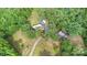 Aerial view of the property surrounded by dense trees, a dirt driveway, and a few other outbuildings at 5523 Flint Ridge Church Rd, Marshville, NC 28103