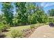 Backyard showcasing a manicured lawn with flower beds and a gravel path at 6136 Sandy Point Ln, Belmont, NC 28012