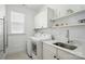 Bright laundry room with modern appliances, sink, storage cabinets, and shelving at 6136 Sandy Point Ln, Belmont, NC 28012