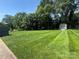 Lush green backyard with perfectly striped lawn and mature trees offering plenty of shade at 6339 River Front Dr, Harrisburg, NC 28075