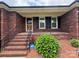 Inviting front porch with brick steps, black railing, and manicured greenery at 6339 River Front Dr, Harrisburg, NC 28075