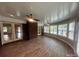 Bright sunroom with wood-look floors, brick accents, fan, and large windows offering a serene view at 6339 River Front Dr, Harrisburg, NC 28075