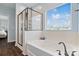 Bright bathroom features a glass enclosed shower, soaking tub, modern fixtures, and natural light at 7318 Rupell Dr, Charlotte, NC 28273