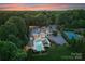 Expansive estate featuring a luxurious pool area, lush landscaping, and a distant city skyline at sunset at 8300 Fairview Rd, Charlotte, NC 28226