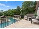 Balcony overlooking a pool and outdoor living area surrounded by lush trees and blue skies at 8300 Fairview Rd, Charlotte, NC 28226