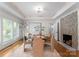 Stylish dining room with a cozy fireplace, a modern chandelier, and a large window at 8300 Fairview Rd, Charlotte, NC 28226