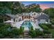 Stunning pool area surrounded by luxurious cabanas, lush landscaping, and a beautifully designed home at twilight at 8300 Fairview Rd, Charlotte, NC 28226