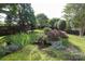 Serene backyard with a charming pond, lush greenery, trees, and landscaping at 10217 Falling Leaf Dr, Concord, NC 28027