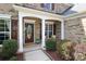 Cozy front porch featuring a stylish front door, seating, and professionally landscaped flowerbeds at 10217 Falling Leaf Dr, Concord, NC 28027