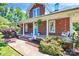 Charming brick home featuring a spacious front porch with white columns and inviting porch swing at 1105 S Point Rd, Belmont, NC 28012