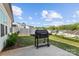 Backyard with concrete patio, grill, green lawn, and view of neighboring houses with white fence at 122 Dyssa Loop, Statesville, NC 28625