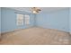 Bright bedroom with neutral carpet, pale blue walls, ceiling fan and double windows at 12724 Frank Wiley Ln, Charlotte, NC 28278