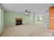Bright living room with neutral carpet, fireplace, ceiling fan, and staircase at 12724 Frank Wiley Ln, Charlotte, NC 28278