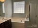 Bright bathroom featuring a bathtub, glass block window, and brown sink vanity at 13123 Ashley Meadow Dr, Charlotte, NC 28213