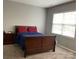 This bedroom features carpet, a wood bed with red pillows, and natural light from the window at 13123 Ashley Meadow Dr, Charlotte, NC 28213