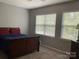 This bedroom features carpet, a wood bed with red pillows, and natural light from two windows at 13123 Ashley Meadow Dr, Charlotte, NC 28213