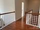 View of hallway with hardwood floors and white railing, leading to the bathroom at 13123 Ashley Meadow Dr, Charlotte, NC 28213