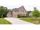 Brick house with three-car garage, long driveway, and manicured lawn at 1445 Cherry Laurel Dr, Waxhaw, NC 28173