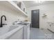 Well-organized laundry room with patterned floors, floating shelves, and modern appliances at 1445 Cherry Laurel Dr, Waxhaw, NC 28173