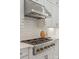 Stovetop with stainless steel vent, white tile backsplash, and white countertops at 1445 Cherry Laurel Dr, Waxhaw, NC 28173