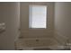 Corner bathtub with jets and a window with blinds for natural light at 14621 Waterside Dr, Charlotte, NC 28278