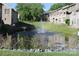 Community pond with a water fountain feature surrounded by mature trees and landscaping at 14621 Waterside Dr, Charlotte, NC 28278