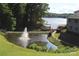 Scenic view of a community pond with a fountain, lush greenery, and waterfront access at 14621 Waterside Dr, Charlotte, NC 28278