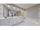 Modern bathroom featuring double sinks, a large mirror, and a soaking tub with marble surround at 15215 Arleta Cir, Charlotte, NC 28277