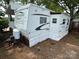 Exterior shot of a trailer home with a white exterior and brown accents, nestled in a wooded area at 164 Dogwood Cir, New London, NC 28127