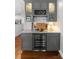 Stylish wet bar with gray cabinetry, granite countertop, wine cooler, and glass display shelves at 19143 Juanita Ln, Cornelius, NC 28031