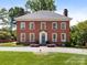 Beautiful brick two-story home featuring mature landscaping, a gray roof, and a blue front door at 208 Huntley Pl, Charlotte, NC 28207