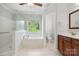 Bright bathroom featuring a glass-enclosed shower, soaking tub and wooden vanity at 2923 Meadow Creek Ln, Monroe, NC 28110