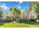 Charming home with lush lawn, mature tree, neutral siding, red shutters and covered entry at 2923 Meadow Creek Ln, Monroe, NC 28110