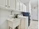 This laundry room features white cabinets, a utility sink and modern washer and dryer at 2923 Meadow Creek Ln, Monroe, NC 28110