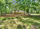 Charming yellow and brick house surrounded by mature trees with a well-maintained lawn and garden at 3203 Oakdale Dr, Monroe, NC 28110