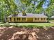 Charming yellow brick and siding home with dormers, surrounded by mature trees and a well-maintained lawn at 3203 Oakdale Dr, Monroe, NC 28110