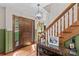 Warm foyer showcasing hardwood floors, decorative wainscoting, and an elegant wooden staircase at 341 N Mulberry St, Statesville, NC 28677