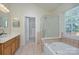 Bright bathroom featuring a tub, shower, double sink vanity, and a doorway to the walk-in closet at 3632 Cole Mill Rd, Charlotte, NC 28270